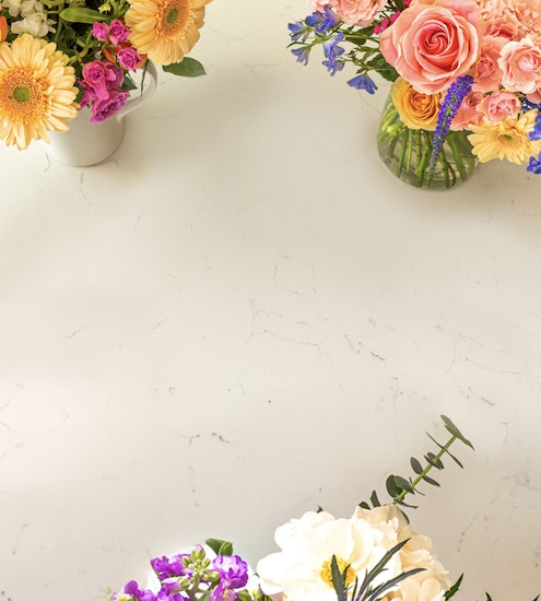 Vibrant floral arrangements featuring roses, daisies, and greenery on a light surface.