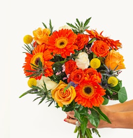 Vibrant bouquet featuring orange gerberas, roses, and yellow accents, perfect for celebrations.