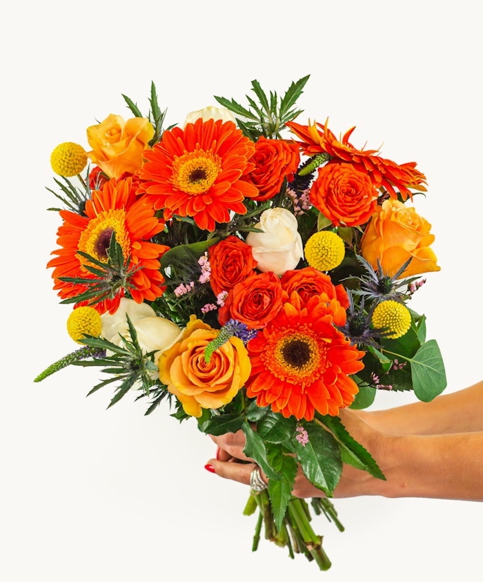 Bright floral bouquet featuring vibrant orange gerberas, roses, and playful yellow accents.