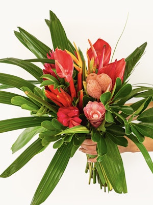 Vibrant tropical flower bouquet featuring red blooms and lush green foliage.