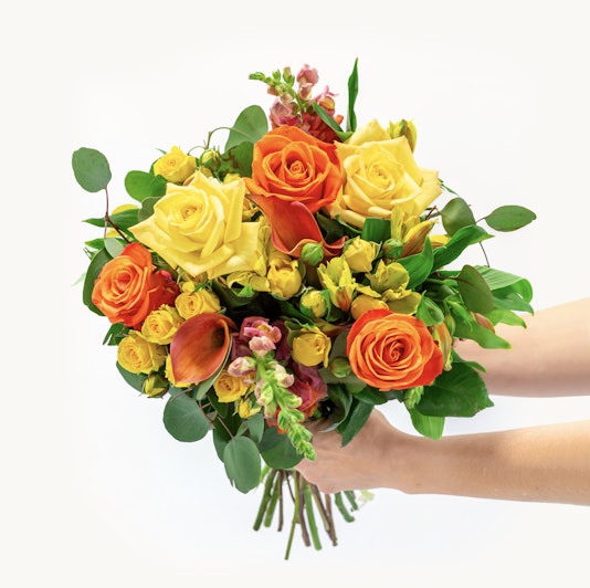 Vibrant bouquet of yellow and orange roses with lush greenery, perfect for any celebration.