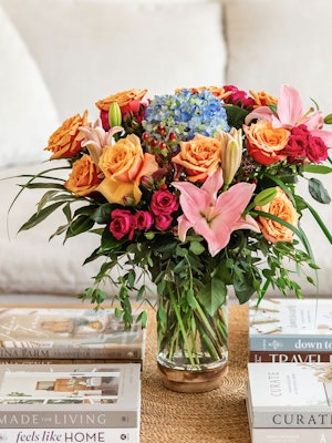 Vibrant floral arrangement featuring roses, hydrangeas, and lilies in a chic glass vase.