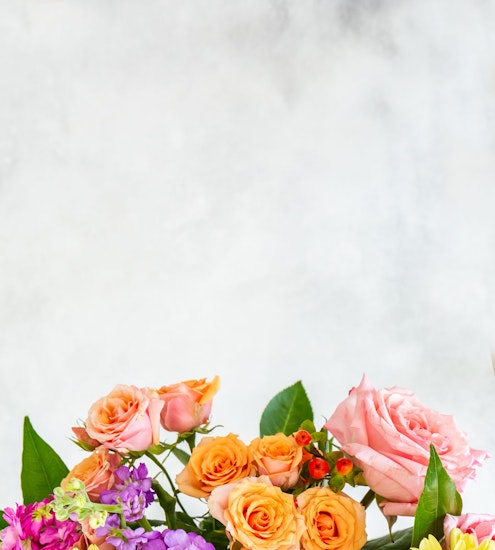 Vibrant arrangement of pink and orange roses complemented by colorful blossoms, ideal for gifts.