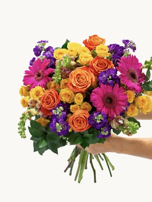 Bright and cheerful bouquet featuring orange roses, pink gerbera daisies, and vibrant green foliage.
