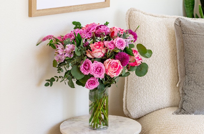 Vibrant bouquet of pink roses and alstroemeria, elegantly displayed in a glass vase.