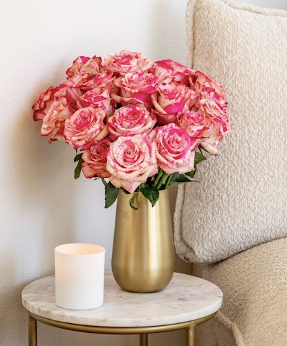A vibrant bouquet of pink and cream roses in a chic gold vase, enhancing home decor.