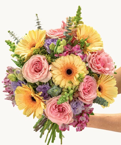 Bright and cheerful bouquet of yellow gerberas, pink roses, and lush greenery.