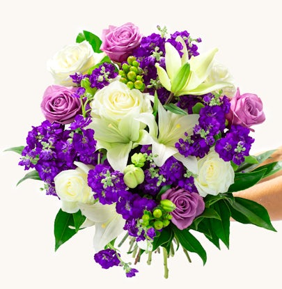 Vibrant bouquet featuring white lilies, purple roses, and lush greenery, ideal for celebrations.